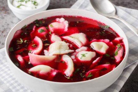 Christmas beetroot soup, borsch with small dumplings with mushroom stuffing closeup on the plate on the table. Horizonta