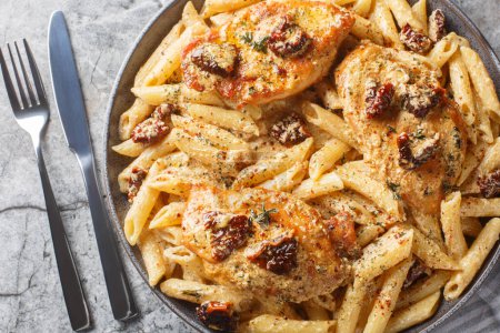 Photo for American Marry Me Chicken pasta with sun-dried tomatoes, cheese, herbs and aromatic creamy sauce close-up in a plate on a marble table. Horizontal top view from abov - Royalty Free Image