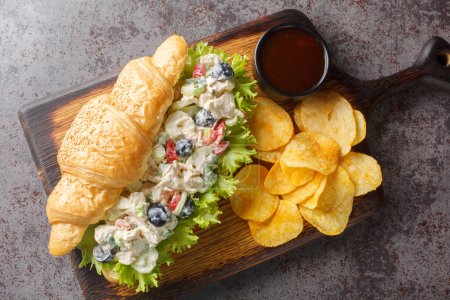 Photo for Chicken salad on a flaky butter croissant with potato chips on a wooden board on the table. Horizontal top view from abov - Royalty Free Image