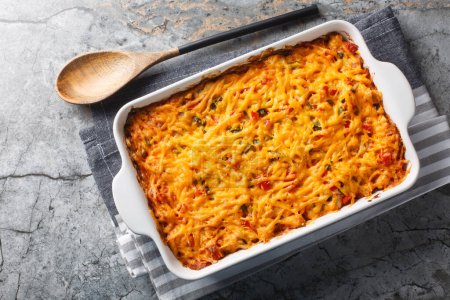 King Ranch Casserole is classic Texas comfort food with vegetables, cheddar cheese, tortilla and cream close-up in a baking dish on a marble table. Horizontal top view from abov
