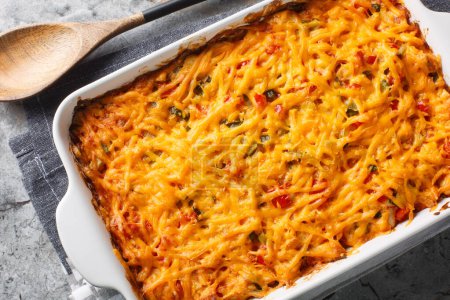 King Ranch Chicken Casserole, Tex-Mex dish of layered tortilla pieces and chicken in a spicy, cheesy sauce close-up in a baking dish on a marble table. Horizontal top view from abov