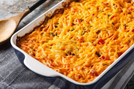 King Ranch Casserole is classic Texas comfort food with vegetables, cheddar cheese, tortilla and cream close-up in a baking dish on a marble table. Horizonta