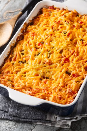 King Ranch Chicken Casserole combines juicy chicken, colorful peppers, tortillas in a bubbly creamy cheesy sauce close-up in a baking dish on a marble table. Vertica