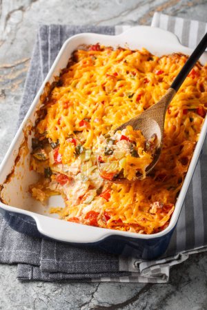 King Ranch chicken casserole is a tender chicken, creamy sauce, tortilla chips and plenty of cheese close-up in a baking dish on a marble table. Vertica
