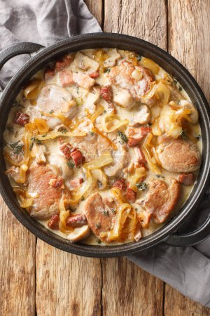 Photo for Danish pork tenderloin that is coupled with onions, bacon and mushrooms all doused in a creamy sauce closeup on the pan on the table. Vertical top view from abov - Royalty Free Image