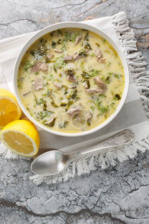 Magiritsa klassische Suppe mit Lamm, Lammnebenerde und Gemüse in Großaufnahme in einer Schüssel auf einem Marmortisch zubereitet. Vertikale Ansicht von oben