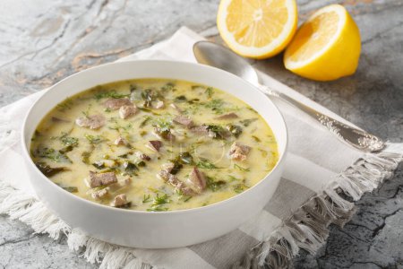 Magiritsa Greek Easter soup with lamb intestines and liver, herbs, seasoned with egg and lemon sauce close-up in a bowl on a marble table. Horizonta