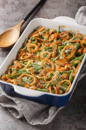 Green beans Casserole and crispy fried onions are tossed in a shortcut creamy mushroom sauce closeup on the baking dish on the table. Vertica