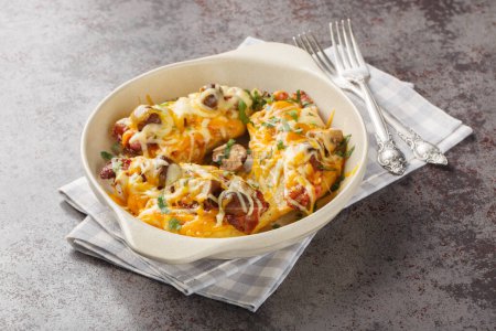 Baked chicken breasts with cheese, mushrooms, bacon close-up in a baking dish on the table. Horizonta