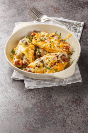 Alice Springs Chicken es un delicioso queso, tocino y champiñones, delicioso primer plano desorden caliente en el plato para hornear en la mesa. Vertica