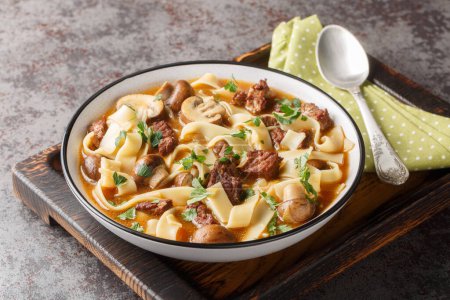 Stroganoff Soup is made with beef steak, mushrooms and noodles in a fragrant creamy broth closeup in a bowl on the table. Horizonta