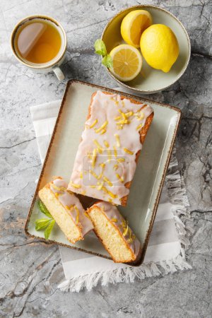 Zitronen-Nieselkuchen hat eine knusprige Zuckerglasur, die sich in Nahaufnahme auf dem Teller auf dem Tisch herauskristallisiert. Vertikale Ansicht von oben