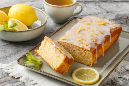 Lemon drizzle cake with lemon zest and icing is a classic British tea-time treat closeup on the plate on the table. Horizonta