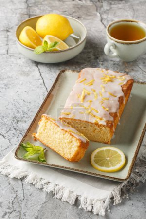 Zitronen-Nieselkuchen hat eine knusprige Zuckerglasur, die sich in Nahaufnahme auf dem Teller auf dem Tisch herauskristallisiert. Vertica