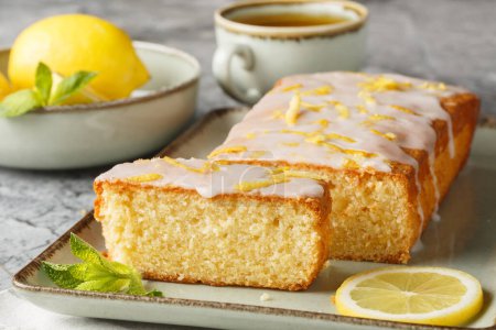 Glazed lemon pound cake loaf with lemon zest closeup on the plate on the table. Horizonta