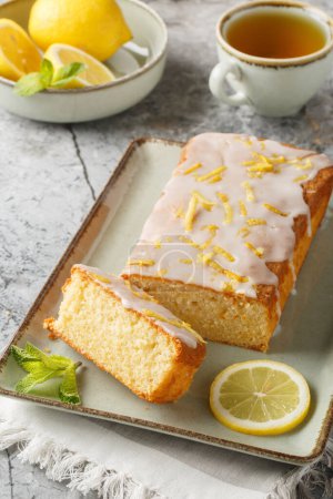 Lemon loaf cake, classic recipe, decorated with sugar icing closeup on the plate on the table. Vertica