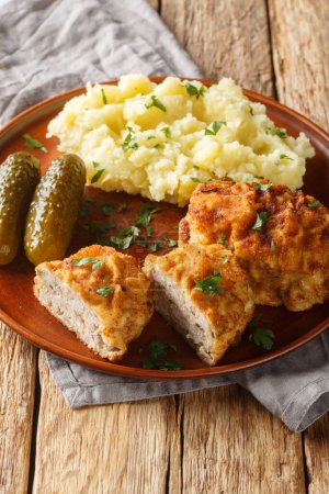 Dutch Schnitzel or Holandsky rizek in Czech, is a combination of delicious pork meat with shredded cheese, herbs served with mashed potatoes closeup on the plate on the table. Vertica