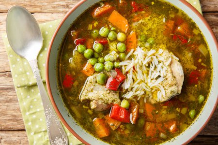 Téléchargez les photos : Aguadito de pollo Soupe péruvienne à la coriandre, légumes et poulet en gros plan sur le bol sur la table en bois. Vue de dessus horizontale d'en haut - en image libre de droit