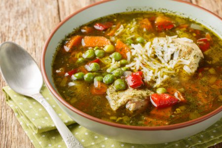 Téléchargez les photos : Soupe de poulet à la coriandre péruvienne ou Aguadito de Pollo avec du riz et des légumes en gros plan sur le bol sur la table en bois. Horizonta - en image libre de droit