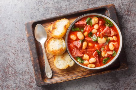 Photo for Spicy stew of lima beans, chorizo and spinach in tomato sauce close-up in a bowl on the table. Horizontal top view from abov - Royalty Free Image