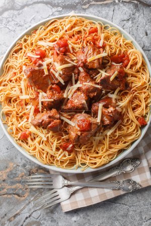 Kokkinisto griego estofado carne de vacuno en salsa roja con espaguetis pasta primer plano en el plato sobre la mesa. Vista superior vertical desde arriba