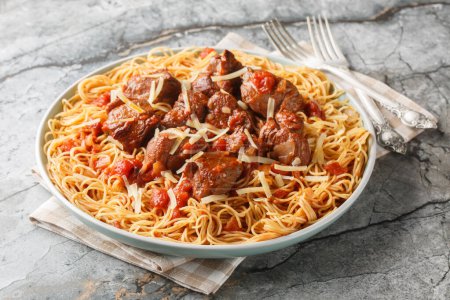 Gedünstetes Rindfleisch in würziger Wein-Tomatensauce, serviert mit Spaghetti in Großaufnahme auf einem Teller auf dem Tisch. Horizonta
