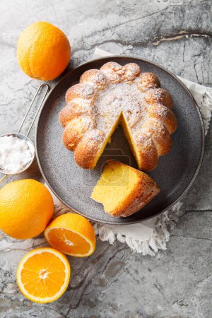 Citrus Orange Pound Cake sprinkled with powdered sugar close-up on a plate on the table. Vertical top view from abov