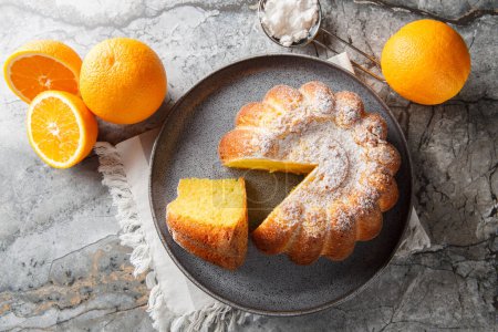 Meskouta is a simple, soft, fluffy orange cake close-up on a plate on the table. Horizontal top view from abov