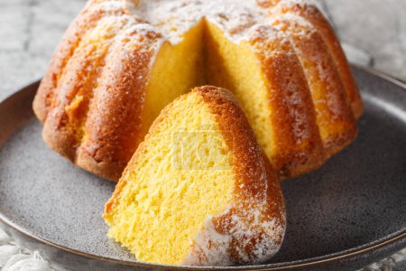 Delicious orange pound cake with zest and orange juice, sprinkled with powdered sugar on a plate on the table. Horizonta