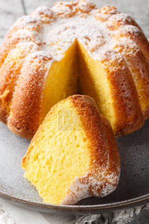 Close-up of Meskouta orange pound cake with powdered sugar on a plate on the table. Vertica