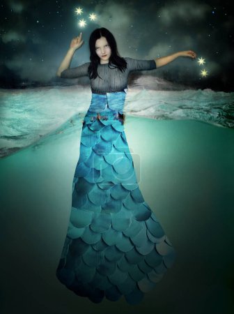 Photo for Beautiful image representing a young mermaid-like woman immersed in water pointing to the stars in the sky - Royalty Free Image