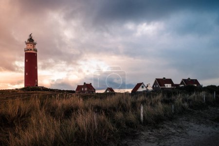 Photo for Red lighthouse at the little isle of Texel, the Netherlands with small small old red h and white houses - Royalty Free Image