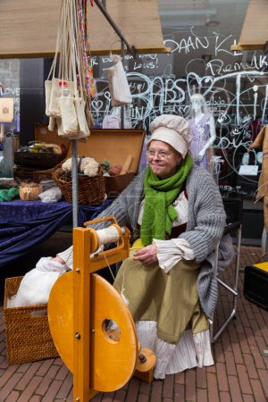 Photo for Brielle,Holland,1-04-2024:a woman in traditional costume is spinning on a spinning wheel during the celebration of the the first town to be liberated from the Spanish in Den Briel in the Netherlands - Royalty Free Image