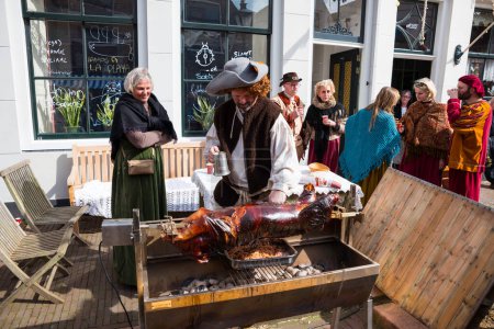 Photo for Brielle,Holland,1-04-2024:man prepares a pig on a spit in traditional traditional costumes celebration of the the first town to be liberated from the Spanish in Den Briel - Royalty Free Image