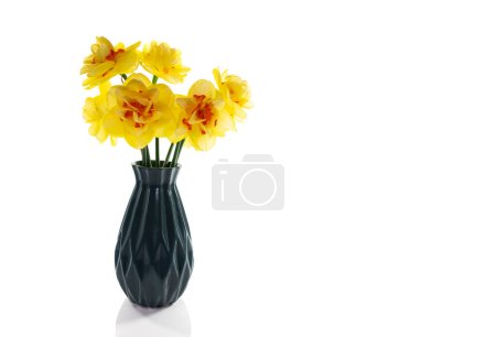 Photo for A still life with a blue vase with yellow daffodils with an orange heart on a white background isolated - Royalty Free Image