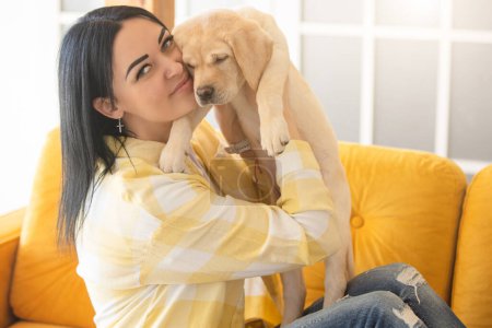Téléchargez les photos : Un petit chiot du Labrador dans les bras de son propriétaire en chemise à carreaux jaune - en image libre de droit