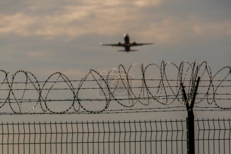 Foto de Avión despega detrás de la valla con alambre de púas - Imagen libre de derechos