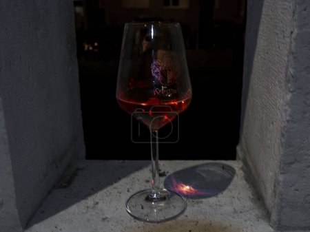 Bodegón con copa de vino tinto por la noche en Szeged con la cresta de la ciudad