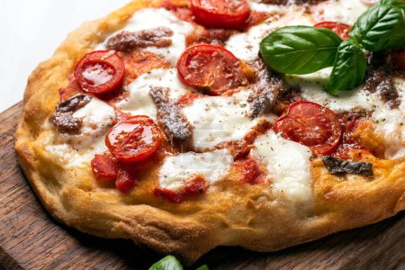 Foto de Pizza con mozzarella, tomate y albahaca en una tabla de madera - Imagen libre de derechos