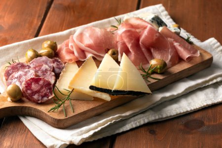 Foto de Platter of sliced prosciutto crudo, salami, pecorino and gorgonzola, delicious italian foods - Imagen libre de derechos