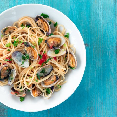 Photo for Plate of delicious Italian spaghetti topped with clams, viewed from above and in square format - Royalty Free Image