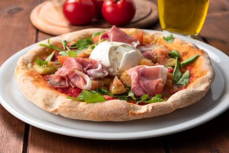 Foto de Delicious italian pizza with prosciutto crudo ham, rocket, tomato sauce, and mozzarella - Imagen libre de derechos