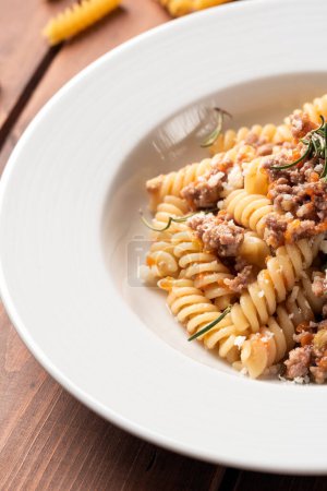 Photo for Plate of delicious fusilli topped with white beef ragu sauce, italian cuisine - Royalty Free Image