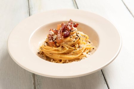Dish of delicious bucatini alla carbonara, a traditional italian recipe of pasta with egg, guanciale and pecorino