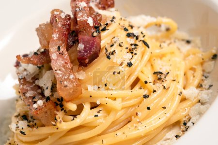 Dish of delicious bucatini alla carbonara, a traditional italian recipe of pasta with egg, guanciale and pecorino