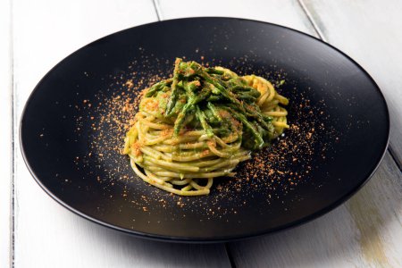 Foto de Plato de deliciosos espaguetis con salsa de espárragos silvestres y bottarga, comida italiana - Imagen libre de derechos