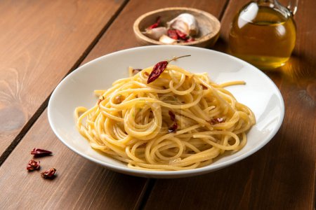 Foto de Placa de deliciosos espaguetis típicos con aceite de oliva, ajo y chile, pasta italiana - Imagen libre de derechos