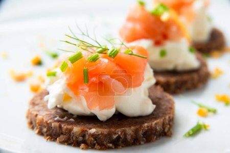 Photo for Dish of delicious canaps topped with smoked salmon and cheese cream, european appetizers - Royalty Free Image