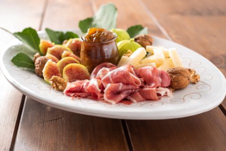 Foto de Bandeja de deliciosos alimentos italianos: jamón fresco, pecorino, mermelada e higos frescos - Imagen libre de derechos
