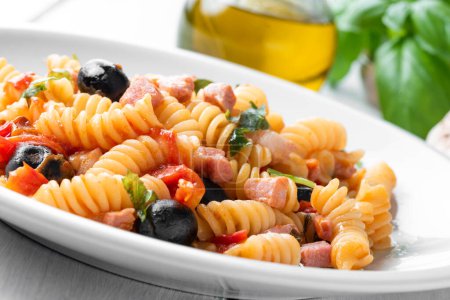 Foto de Deliciosa pasta con salsa de tomate, aceitunas negras, cerdo y aceite de oliva, comida italiana - Imagen libre de derechos